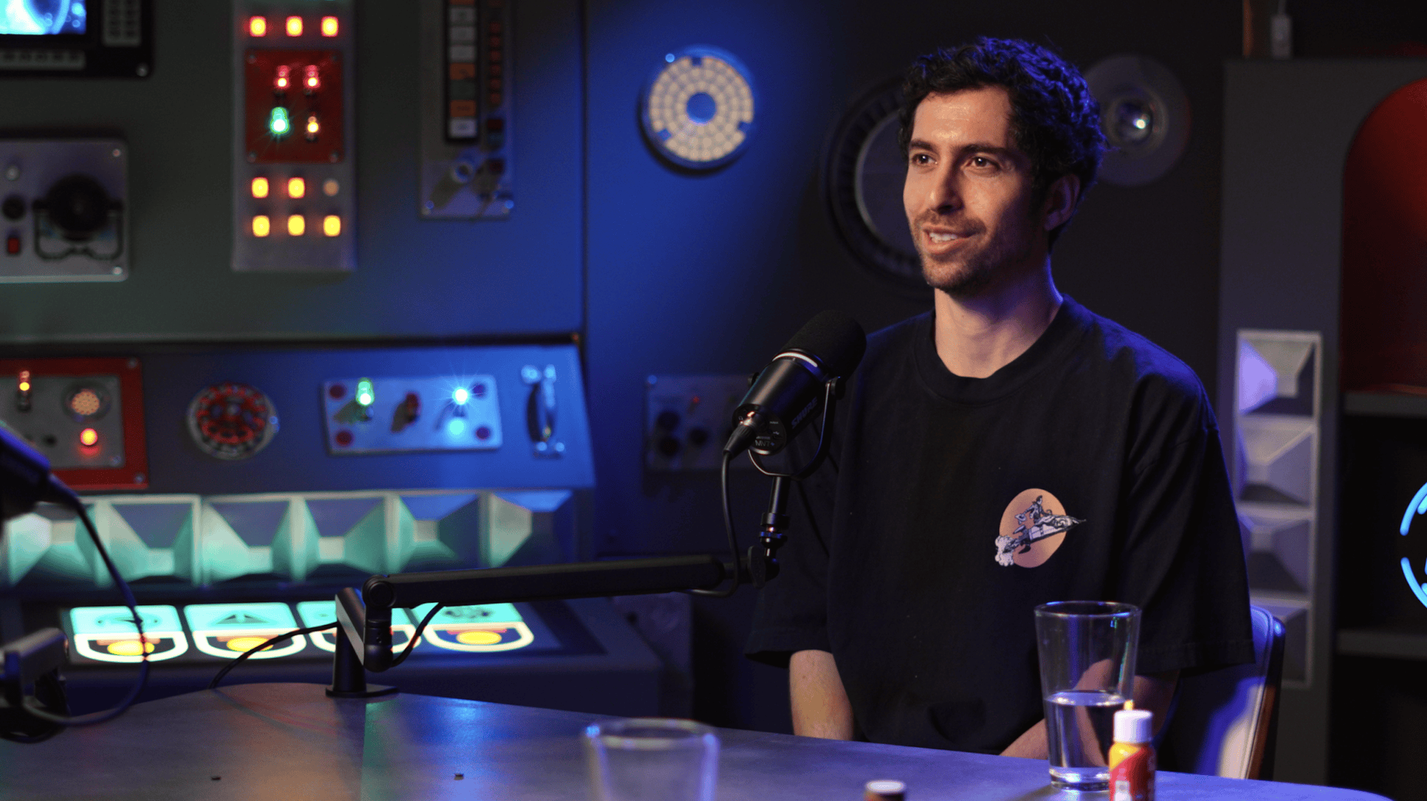 Jesse Michels at the mic on the finished American Alchemy set, lit by its glowing control panels