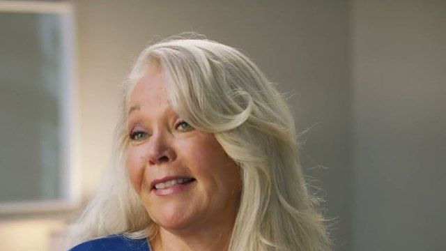 Debbie, a woman with long blonde hair, smiles as she talks during her interview.