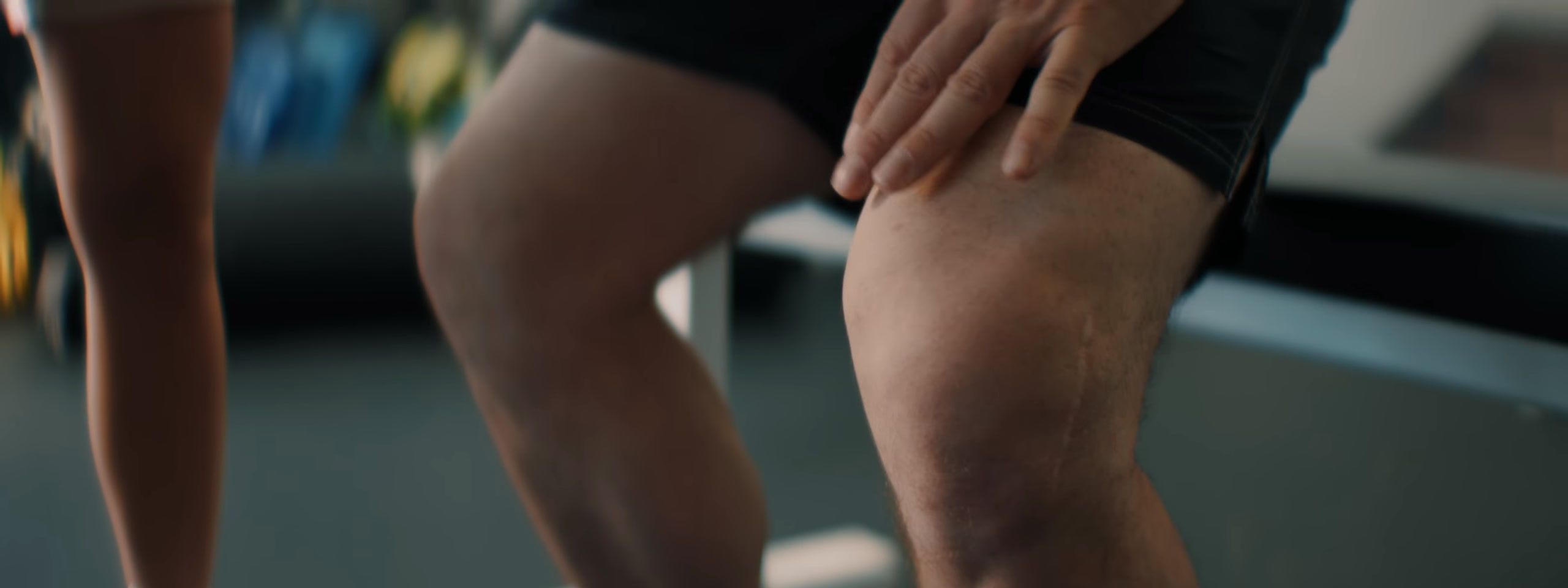 Close-up of a hand pressing on a knee in the gym.