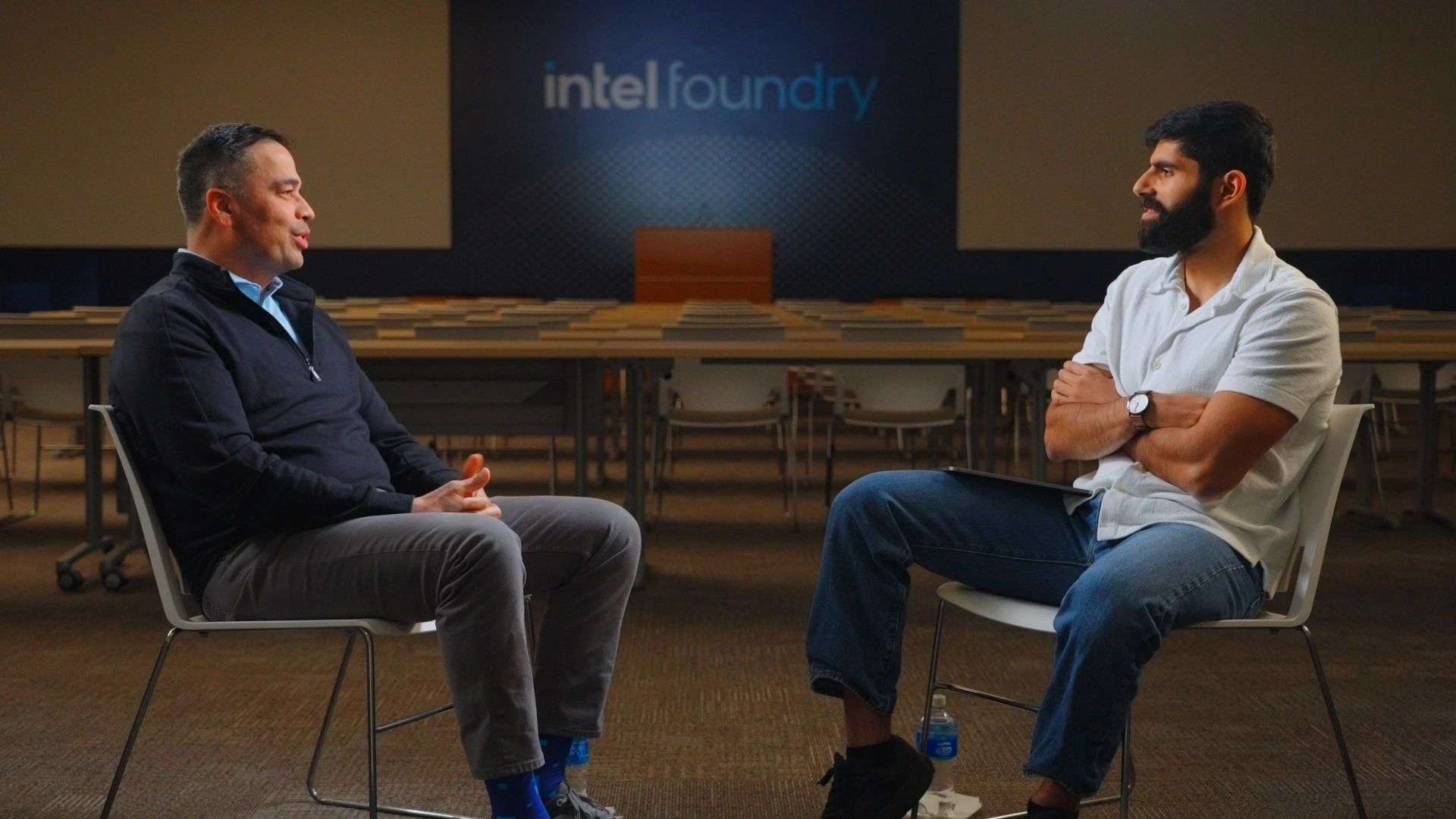 Two men in chairs facing each other for a sit-down interview on an Intel Foundry stage