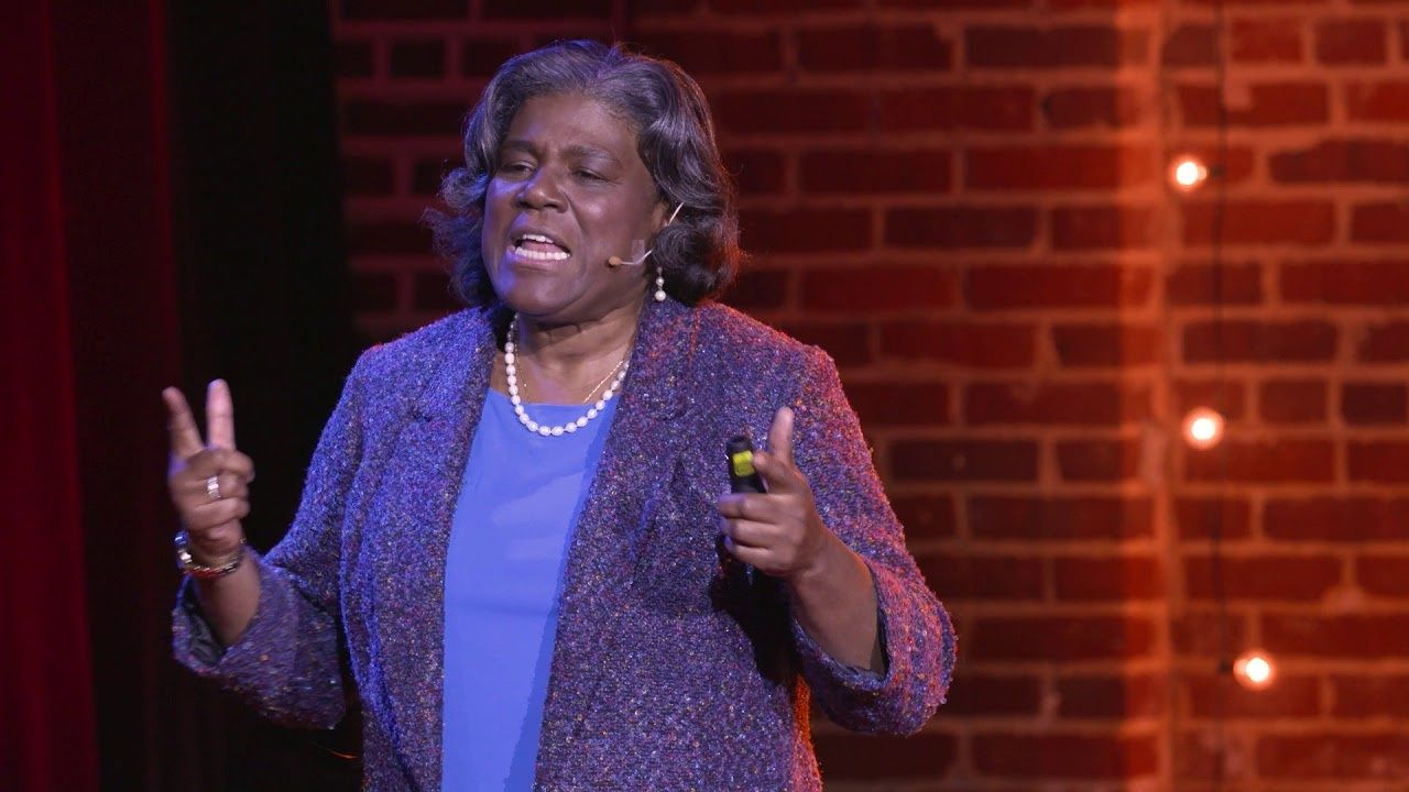 Linda Thomas-Greenfield speaking on the TEDxTysons stage in front of a brick wall.