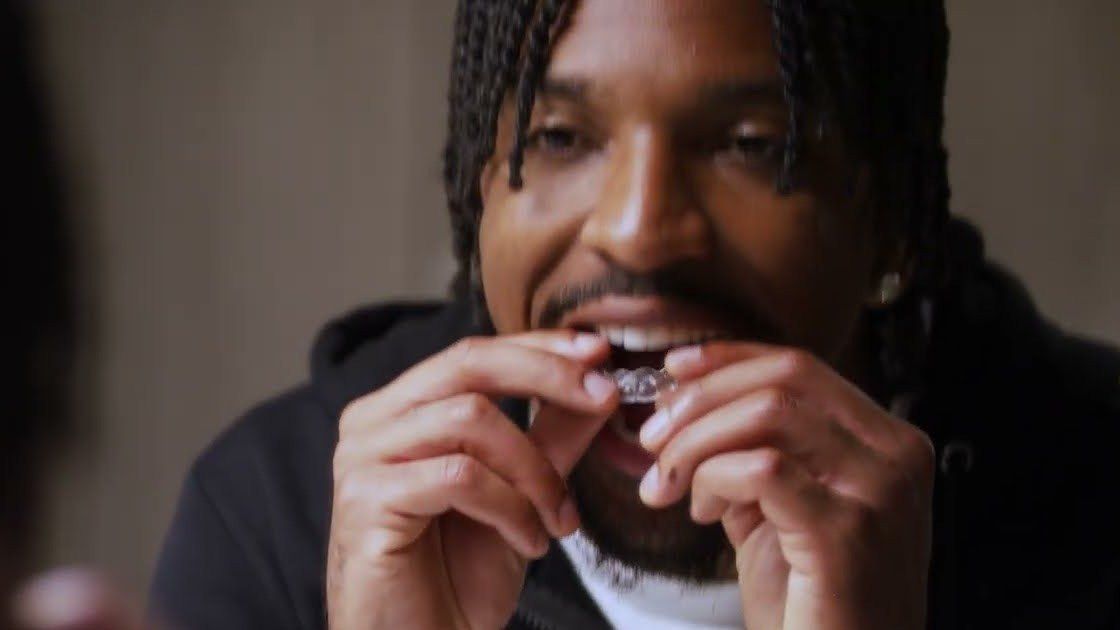 Jayden Daniels smiles while putting in a clear aligner.