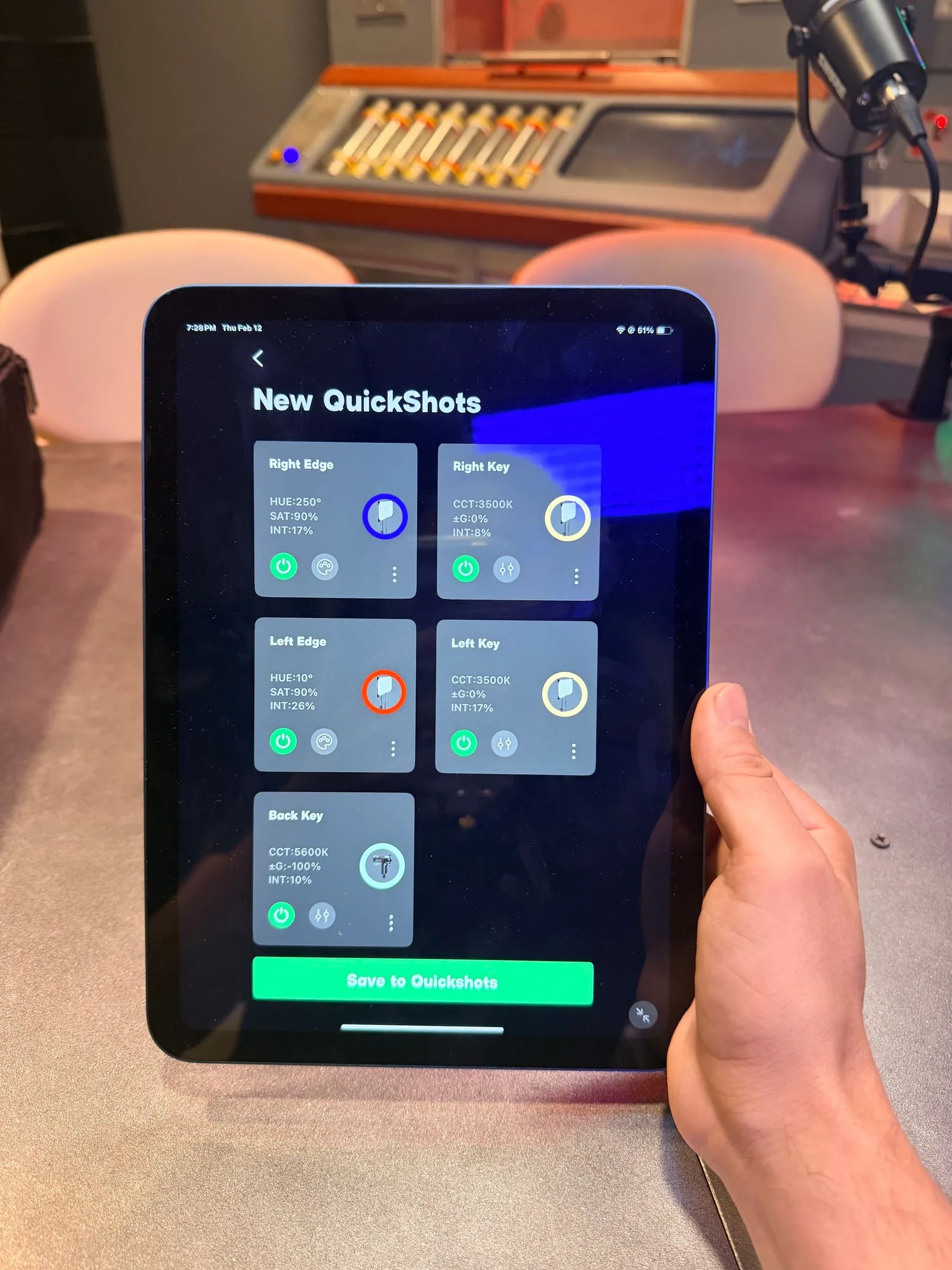 A hand holds an iPad with the studio camera shot presets, the finished set behind it