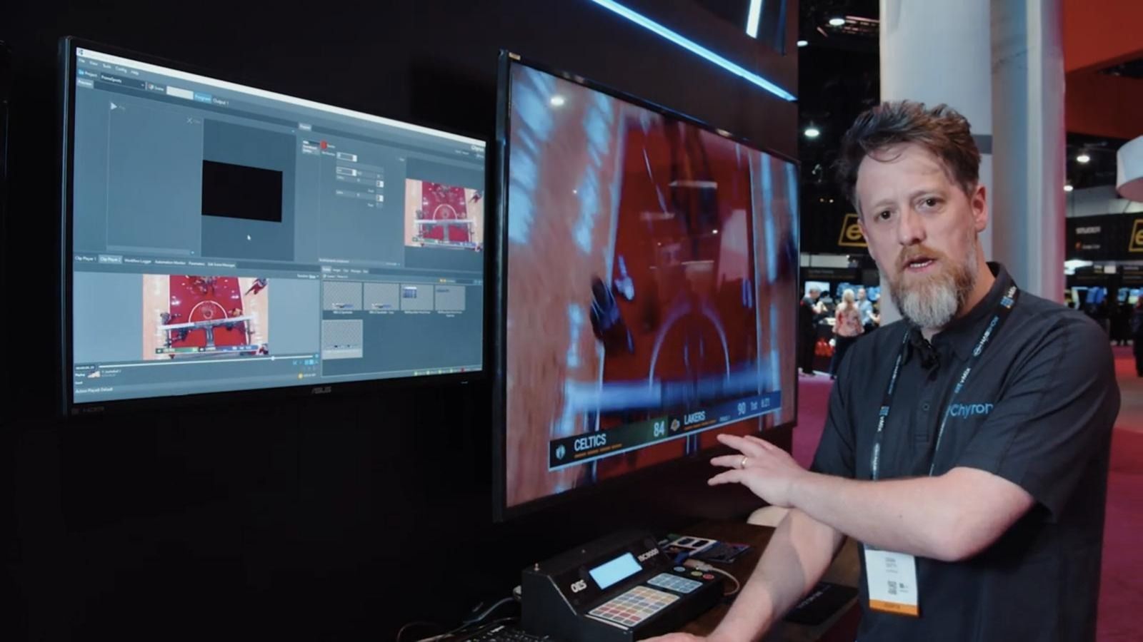 A Chyron pre-sales engineer with his hand on a live sports graphic, two screens of the software beside him